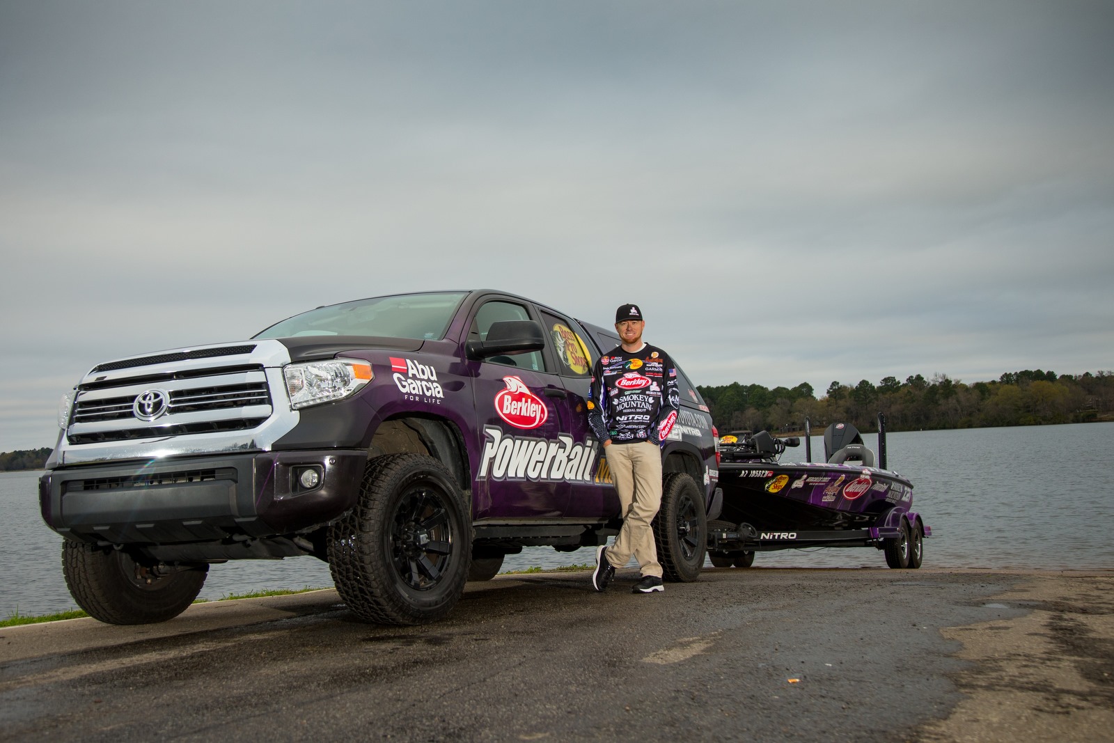 Josh Bertrand, a professional bass angler at Major League Fishing, outside leaning against his vehicle towing a fishing boat on Hercules trailer tires.