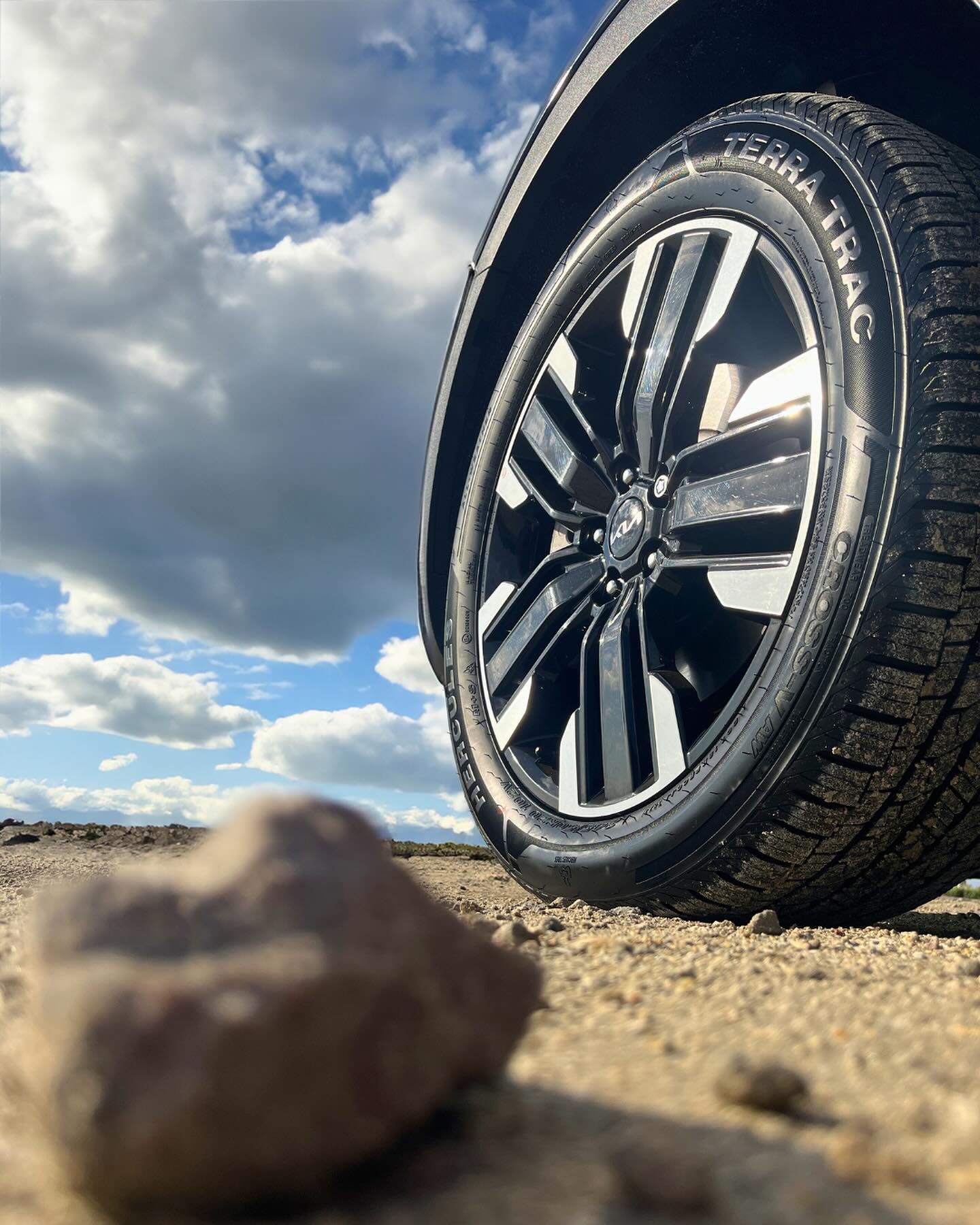 A close-up view of Hercules TERRA TRAC CROSS-V AW tire on the driver's side with a scenic background featuring dessert-like conditions.