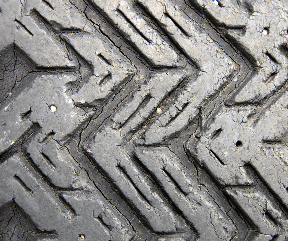 Close-up of a worn and cracked tire tread, showing significant wear and damage to the rubber surface.