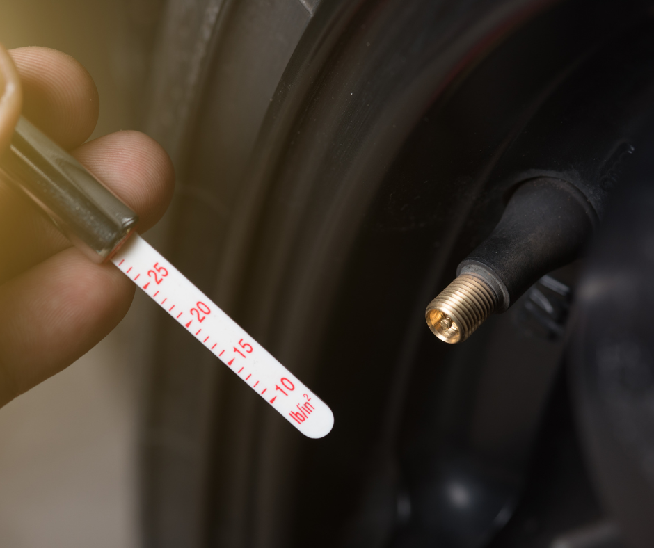 Close-up of a hand holding a tire pressure gauge near a car tire valve, displaying the measurement in PSI.