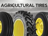 Three Hercules agricultural tires are displayed side-by-side in front of a vast field under a cloudy sky.