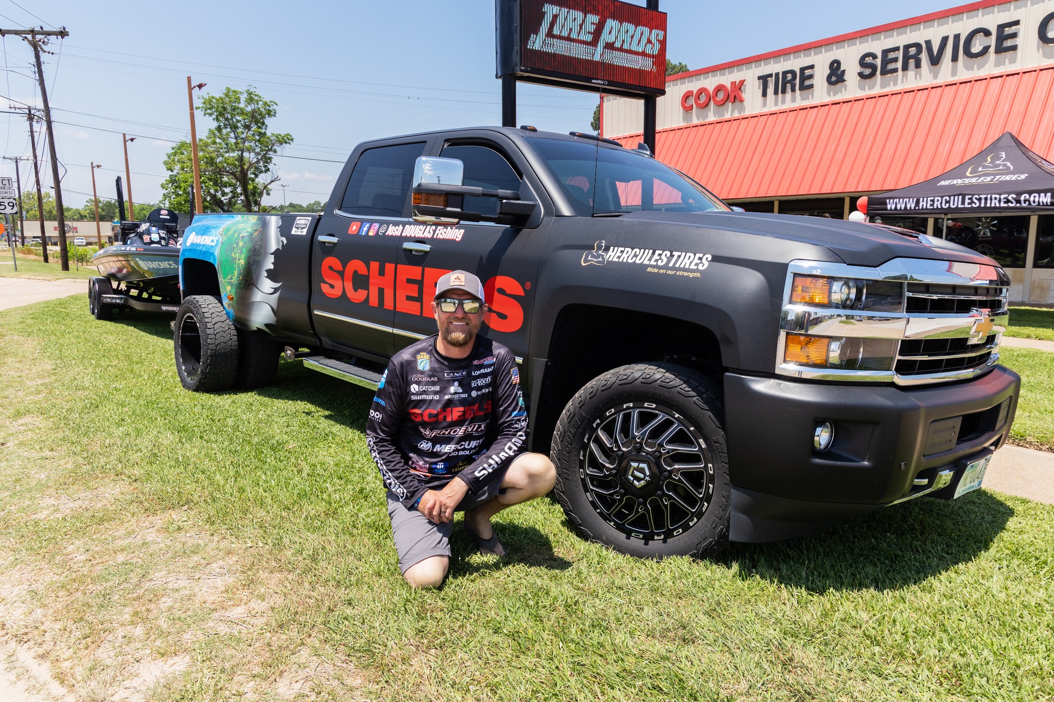 Josh Douglas, a professional bass angler, outside in front of his black truck towing a fishing boat on Hercules trailer tires.