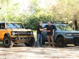 The hosts of Two Guys Garage stand in front of blue and yellow Ford Broncos that are sporting Hercules Tires. 